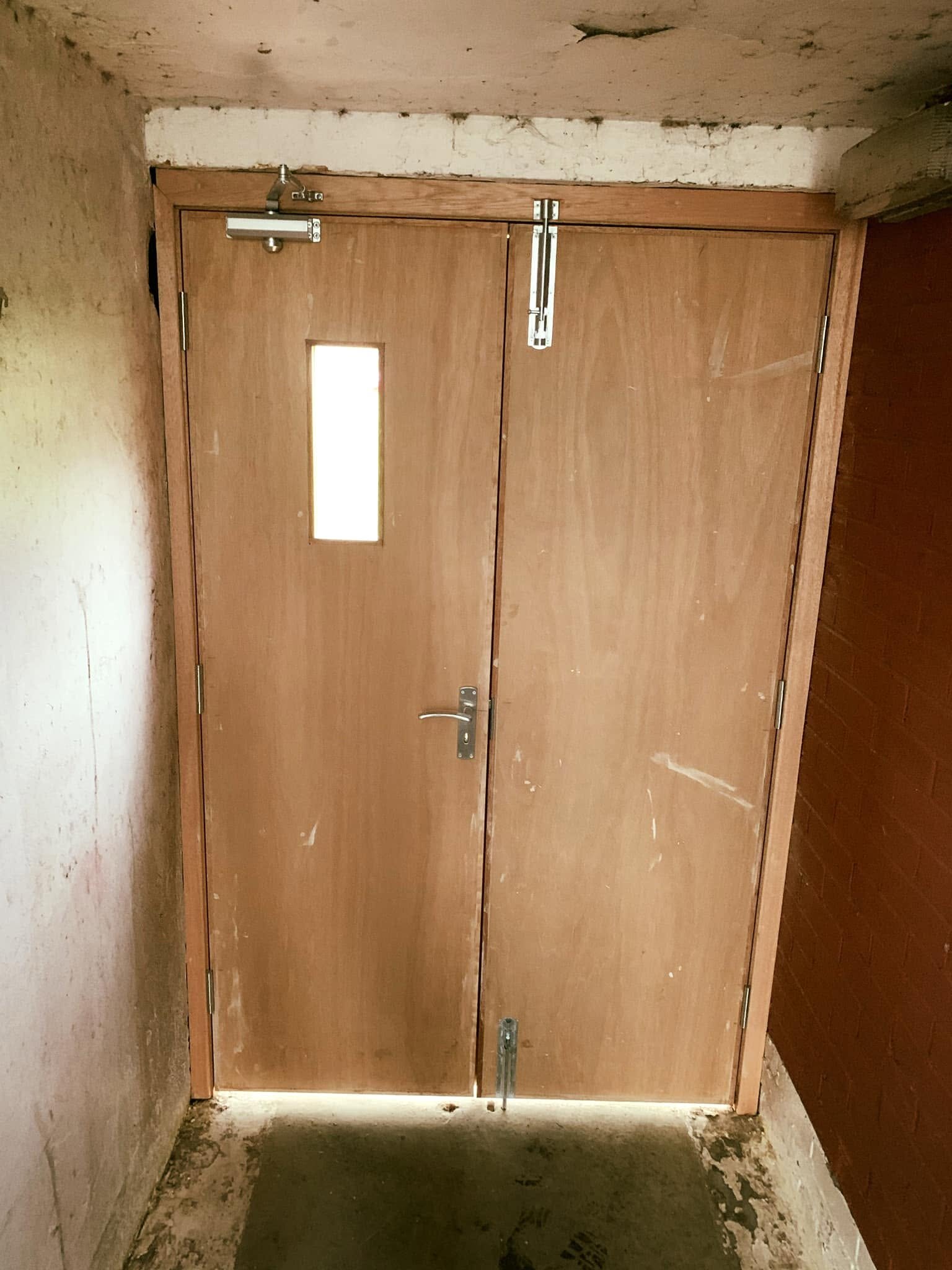 New double doors inside a close — closer, bolts and a vision panel