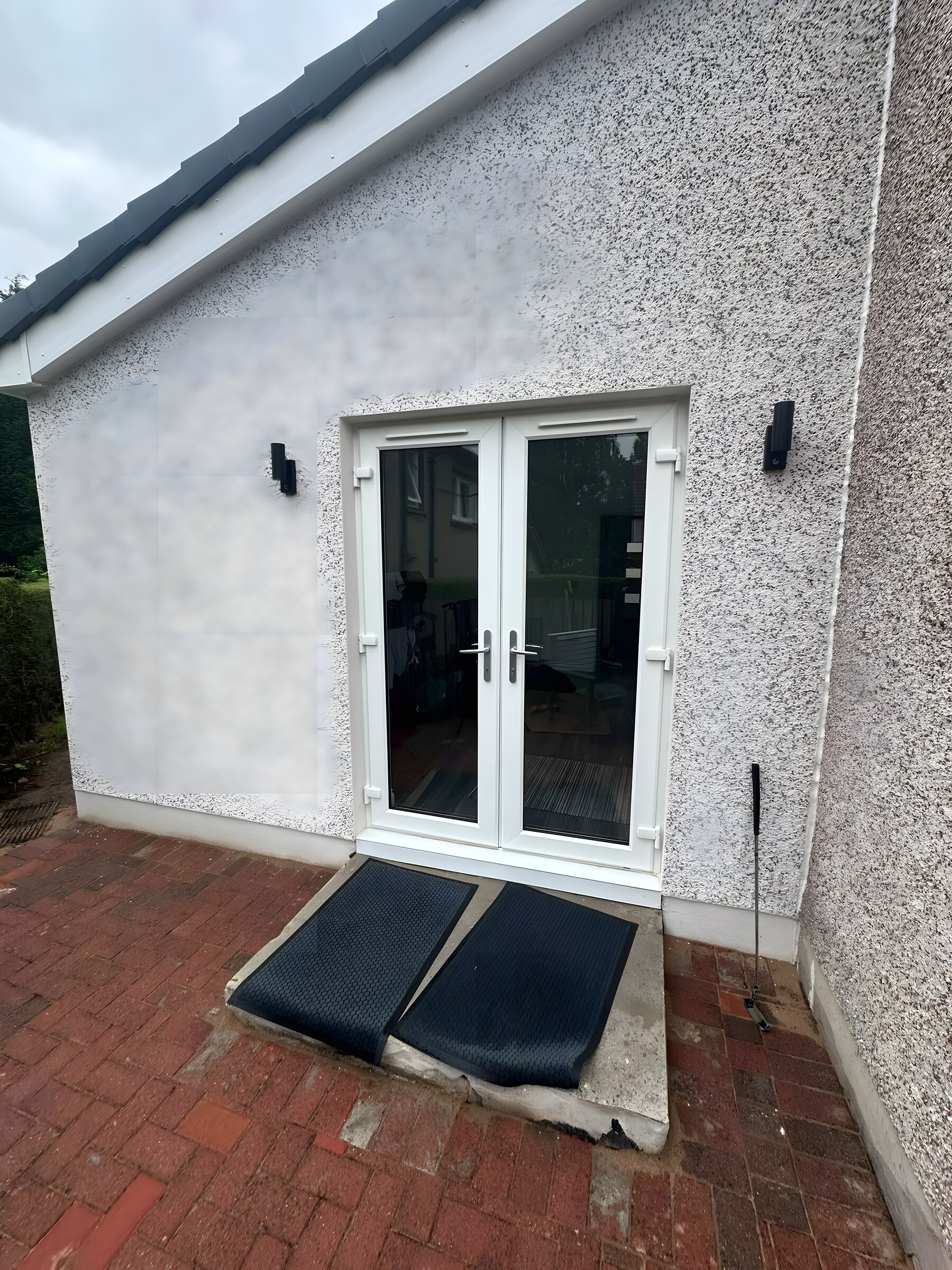 Roughcast, french doors and wall lights — the outside finished