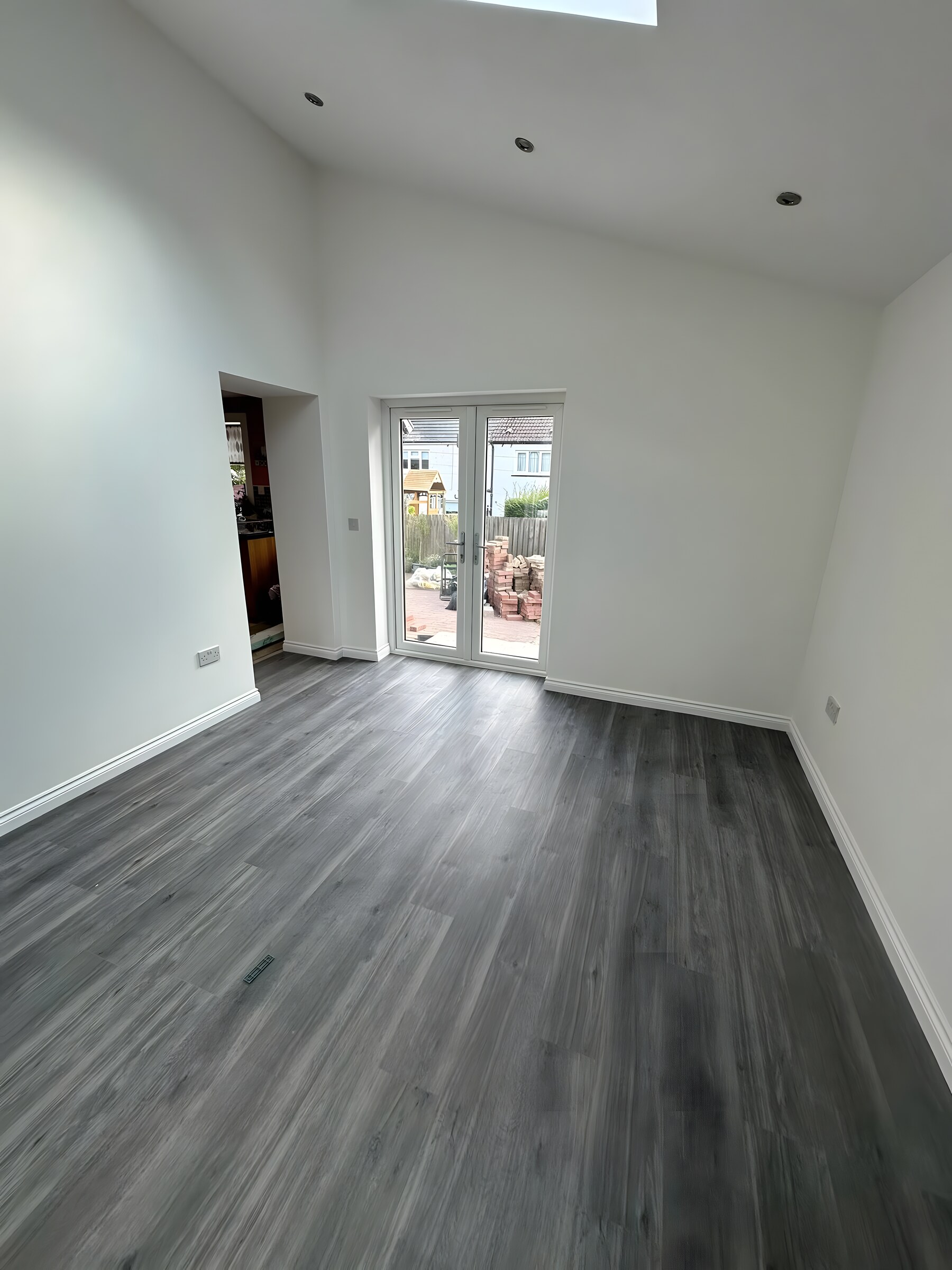 Inside a finished extension — grey oak floor, french doors to the garden