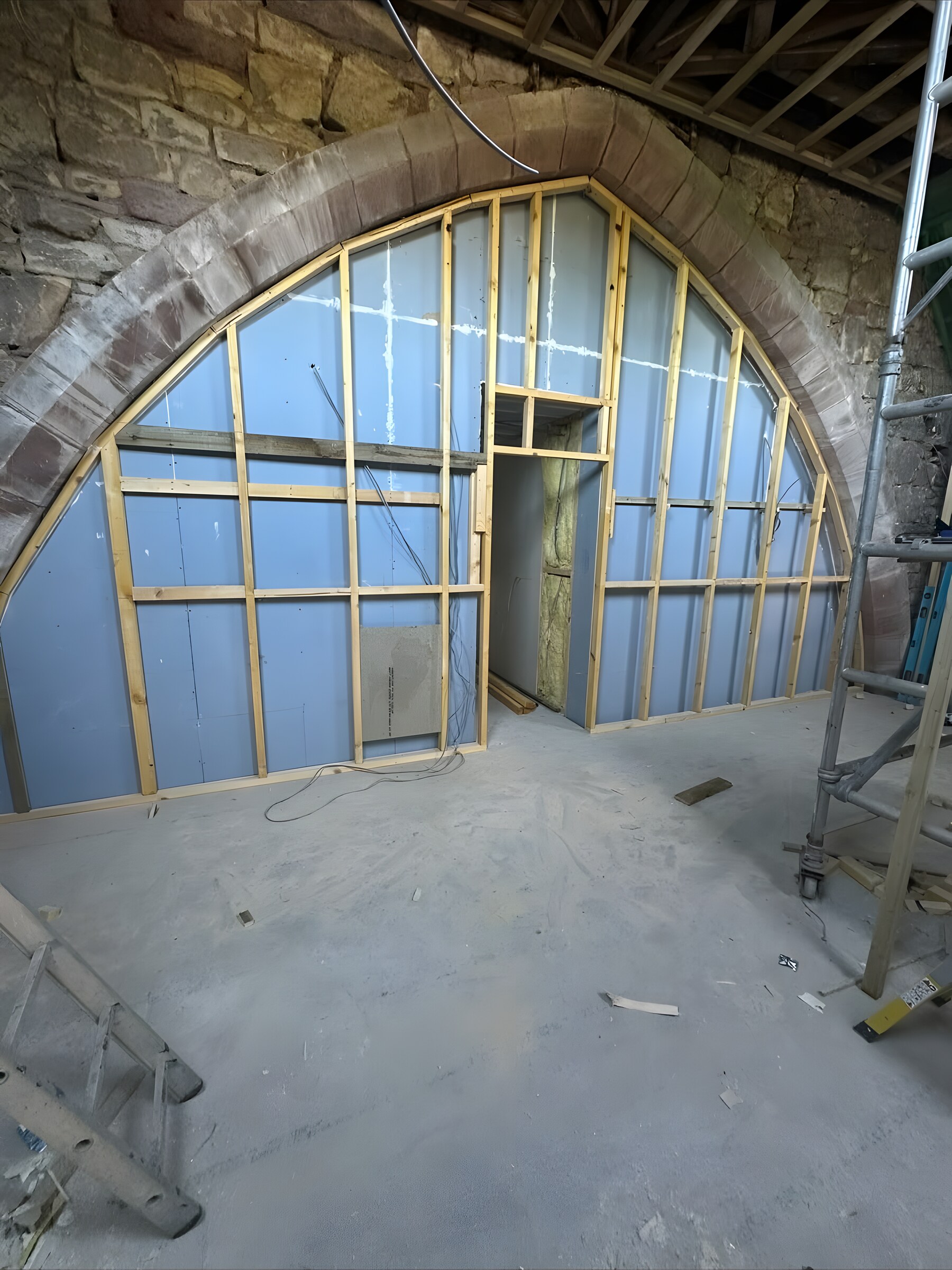 Before — a stud wall framed inside the stone arch, with a door opening