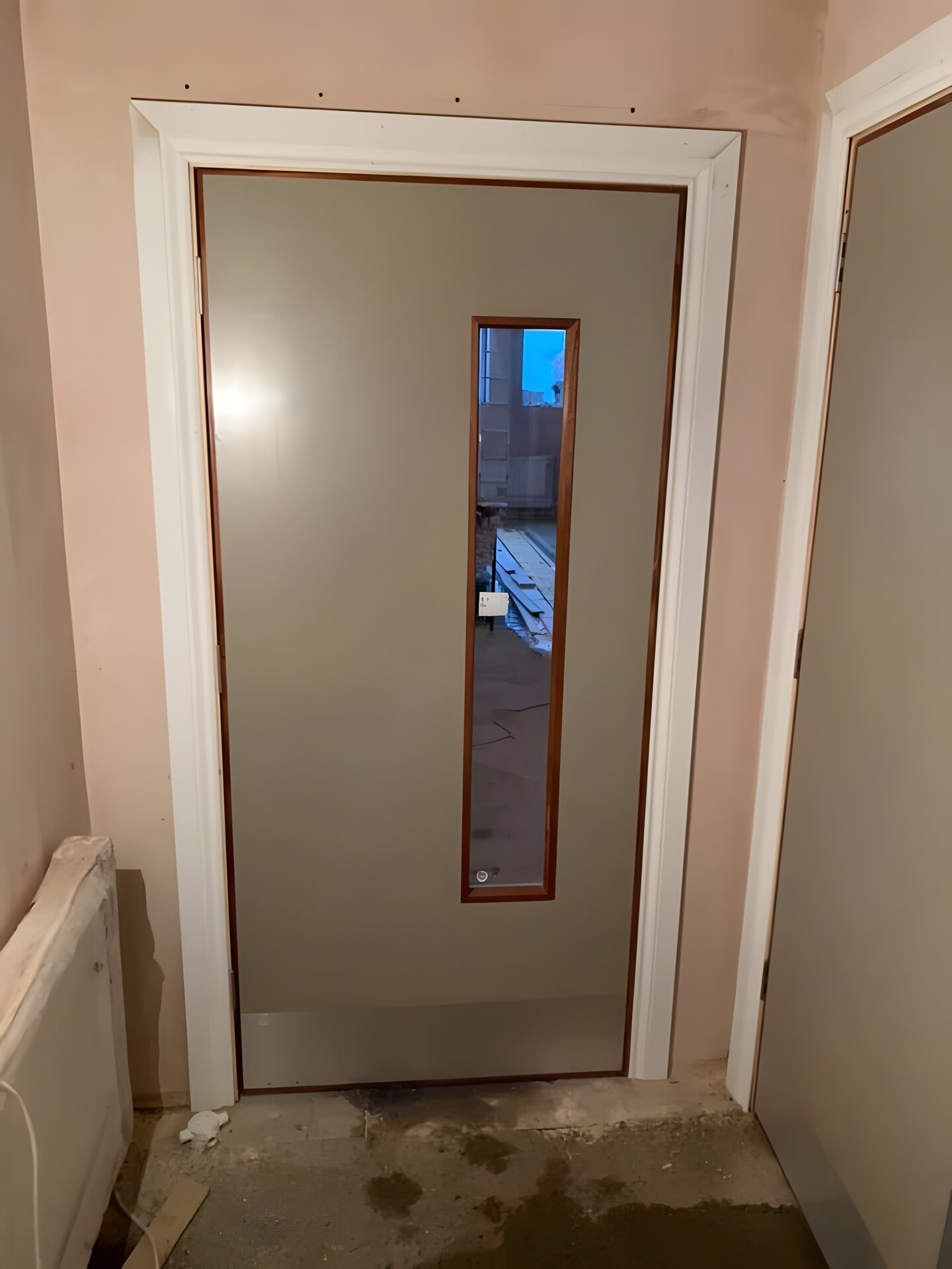 A fire door hung in new linings — vision panel and kick plate