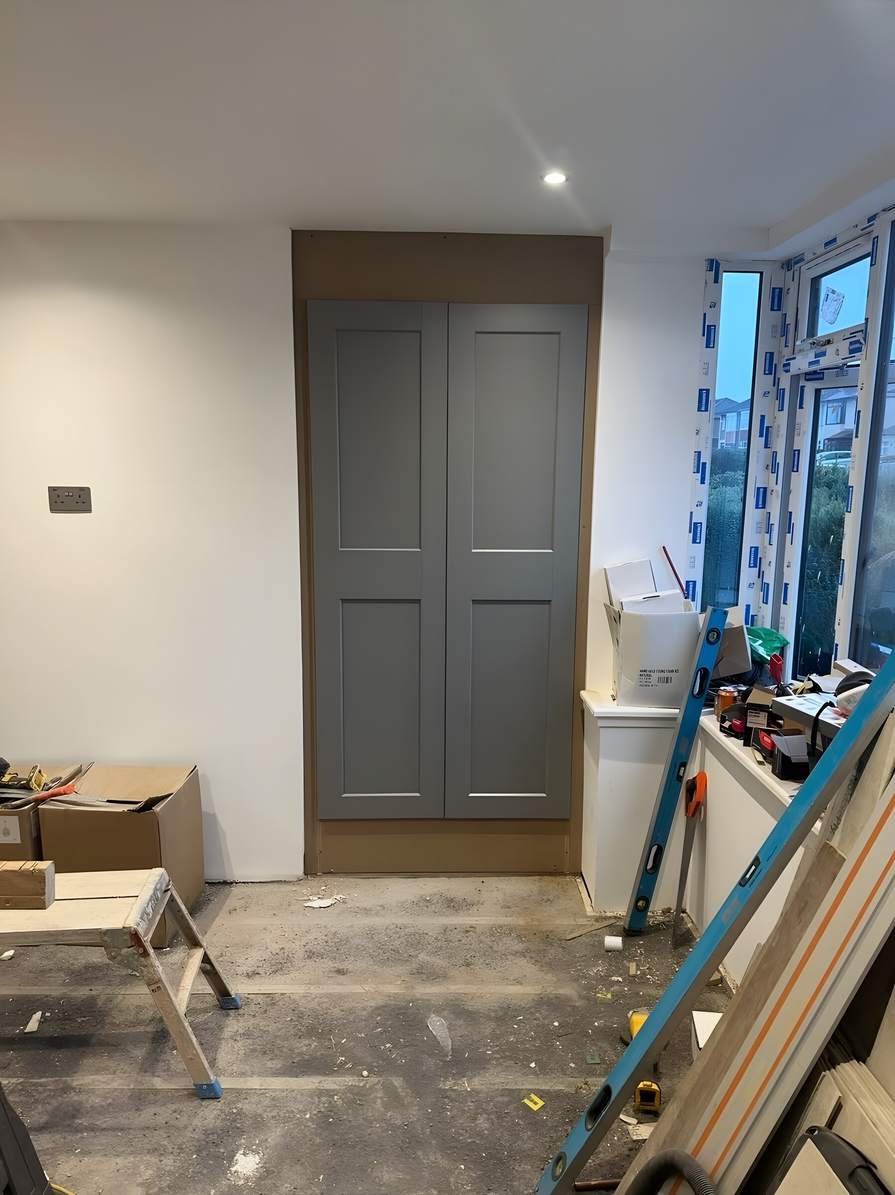 Grey panelled cupboard doors, fitted in a room mid-job