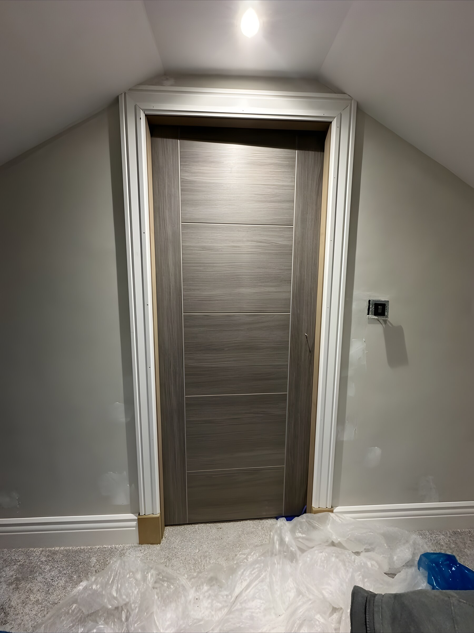 A grey door in a loft room, with the architrave on
