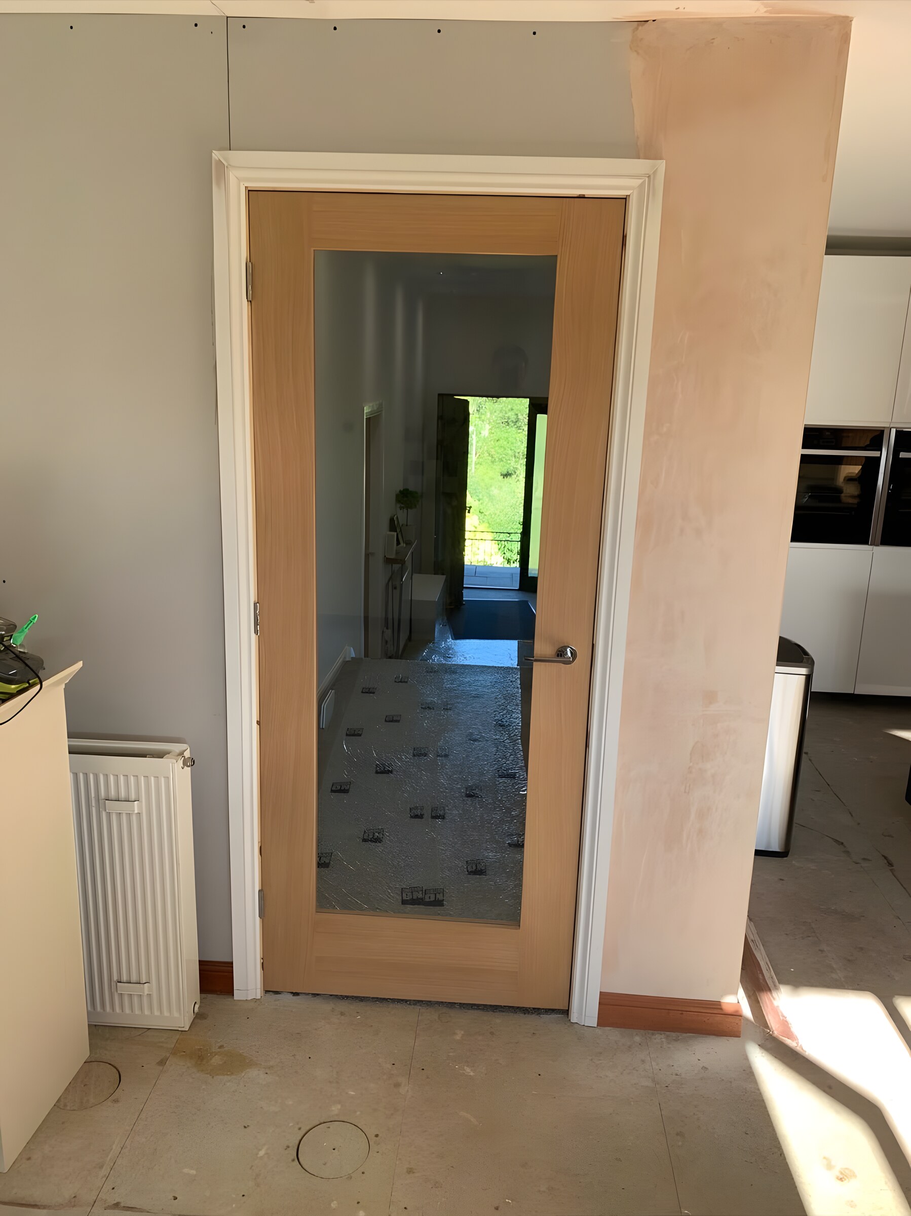 An oak door with a glass panel, hung beside a new kitchen