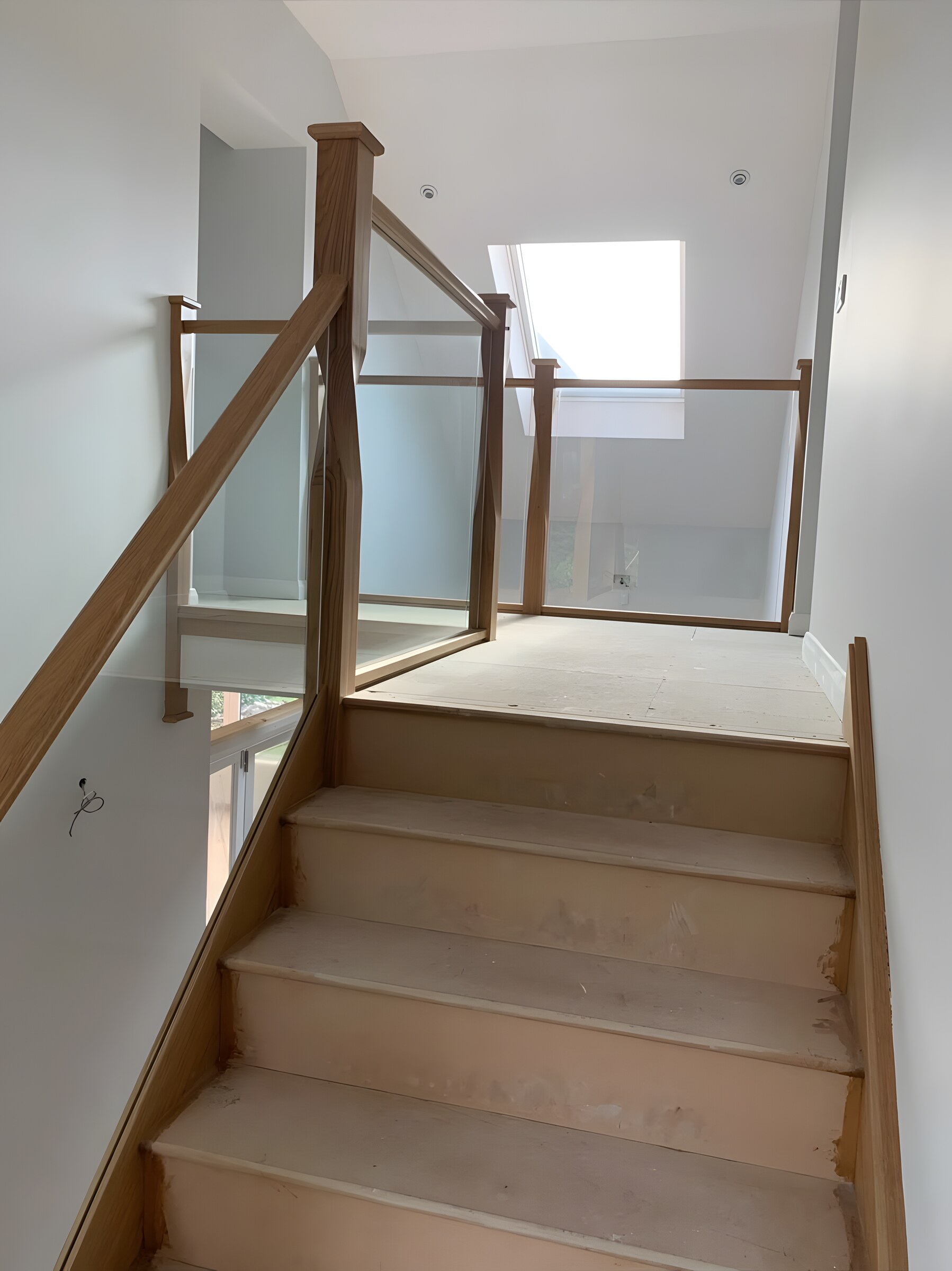 Up to the landing — oak handrail and newels, glass balustrade