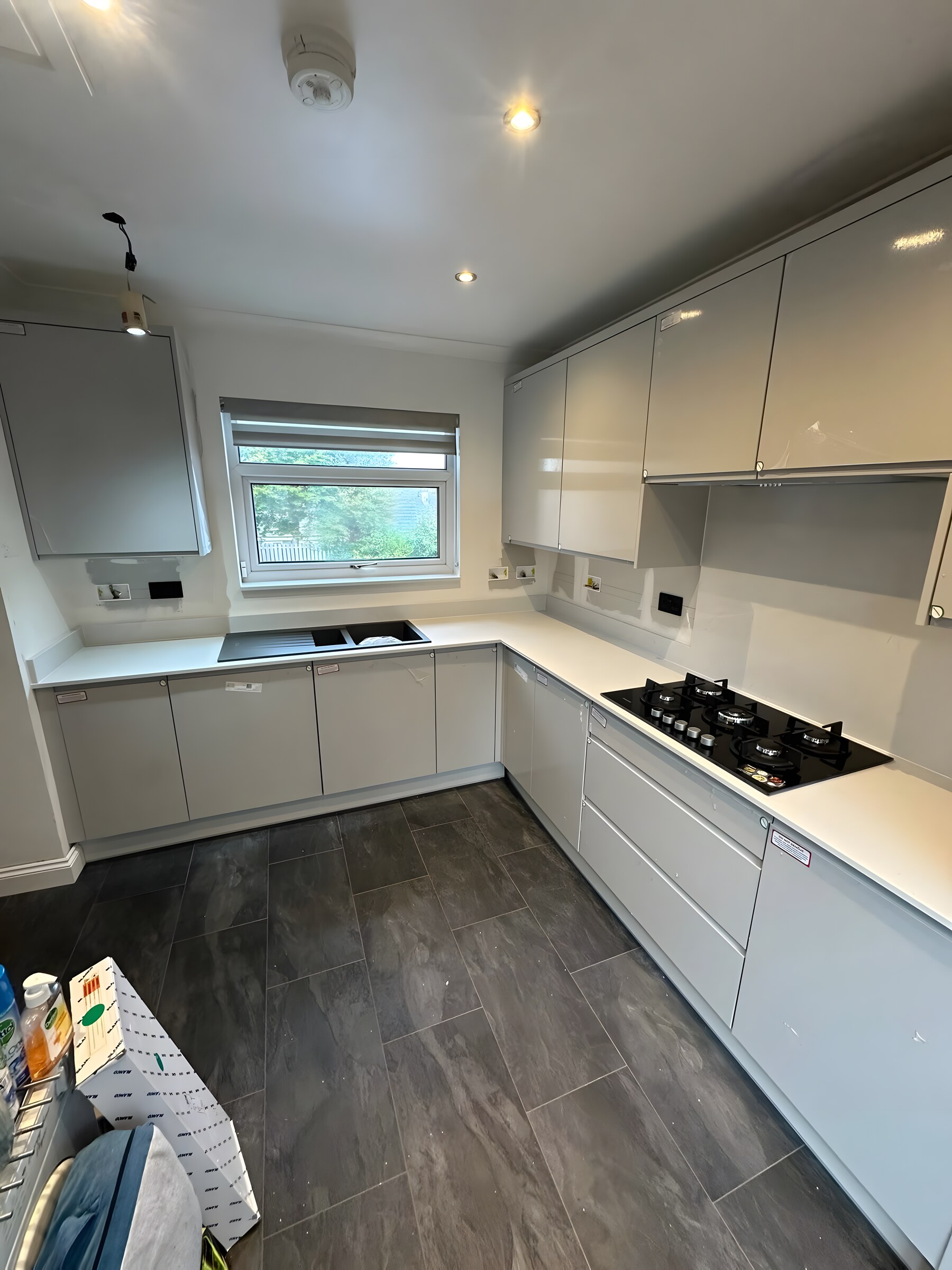 Light grey gloss kitchen with a white worktop and a gas hob, just fitted