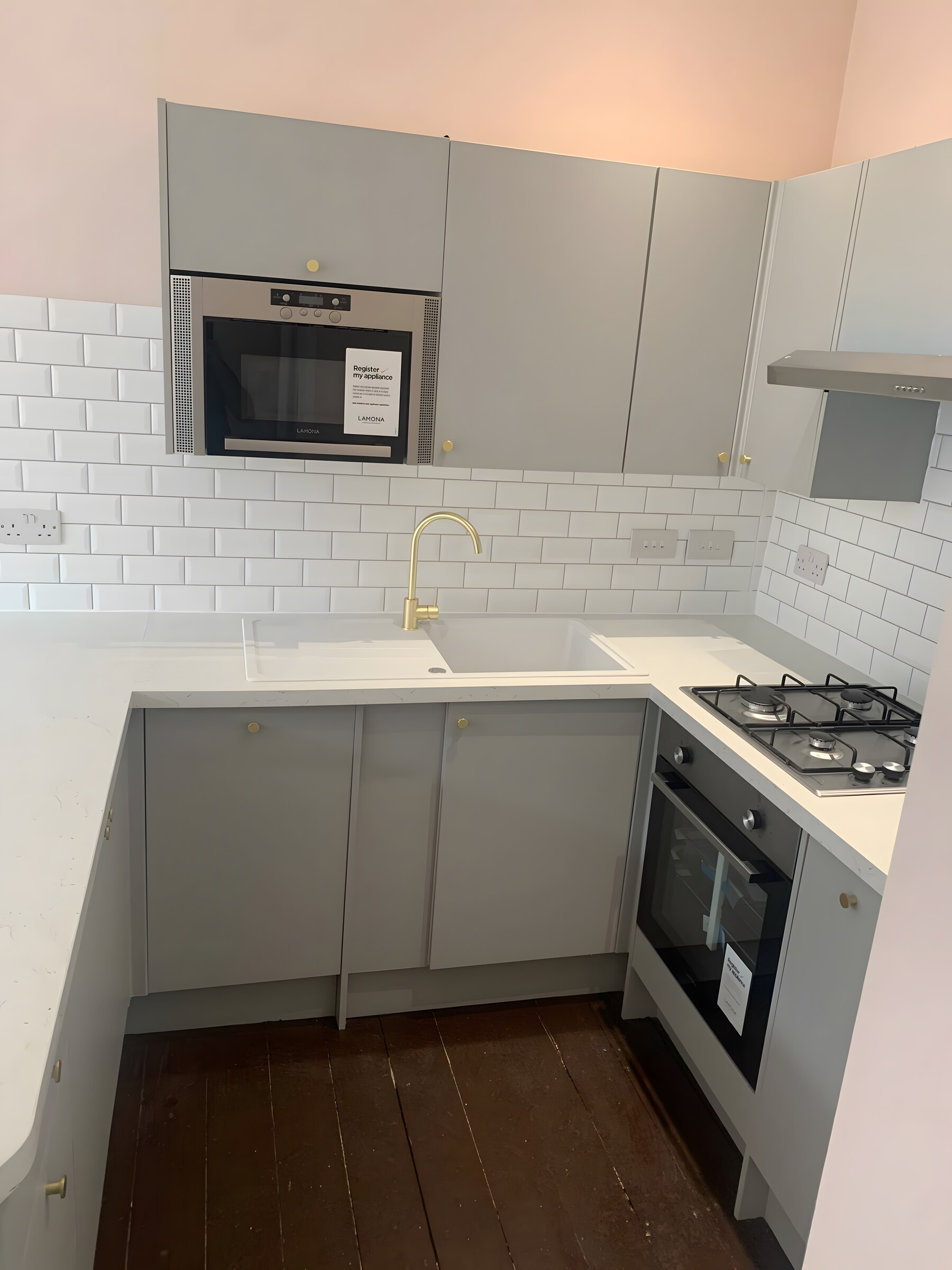 Grey units with brass knobs, white quartz, metro tile and a brass tap