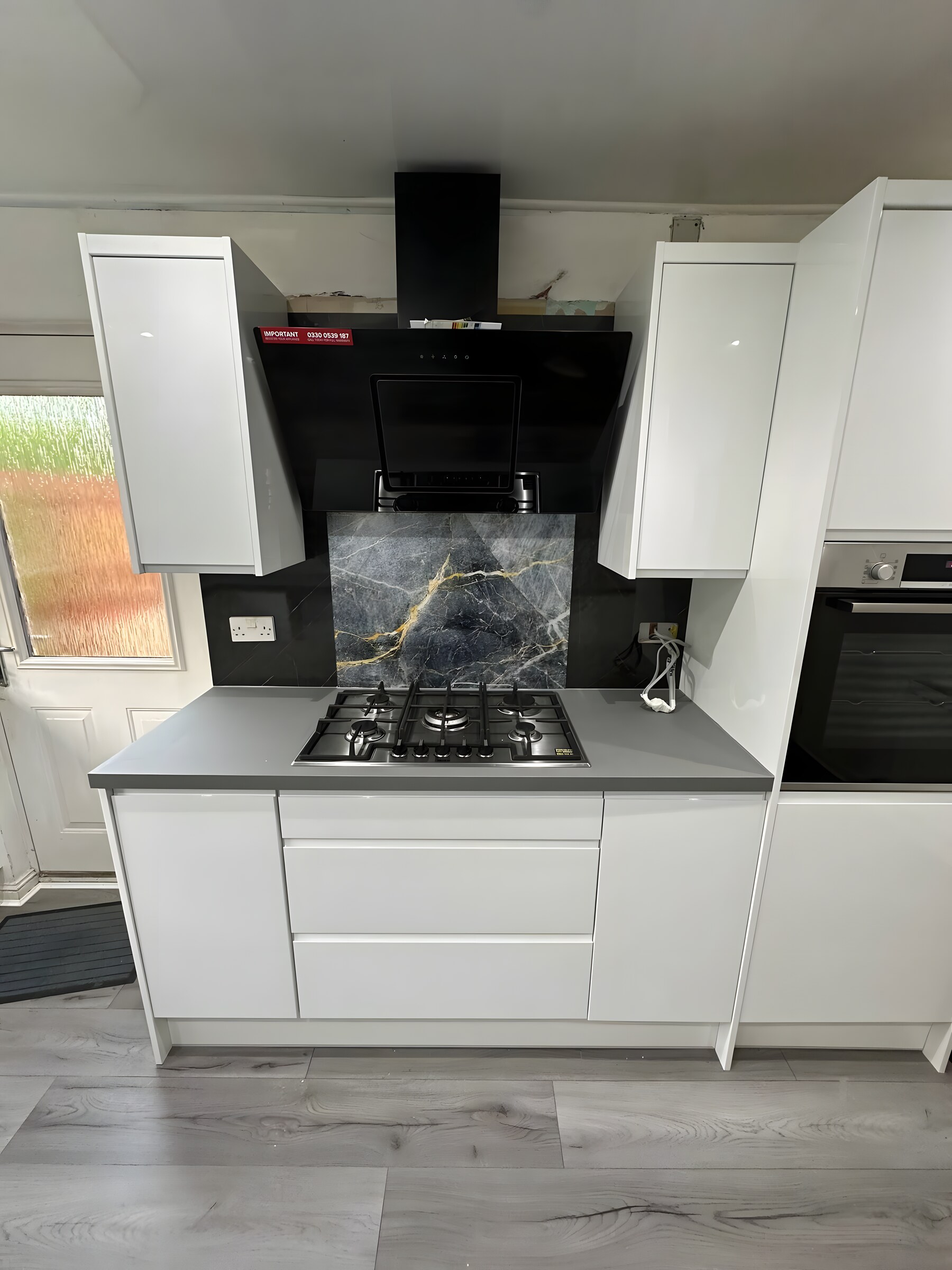White gloss handleless — the hob wall, with the marble-effect splashback
