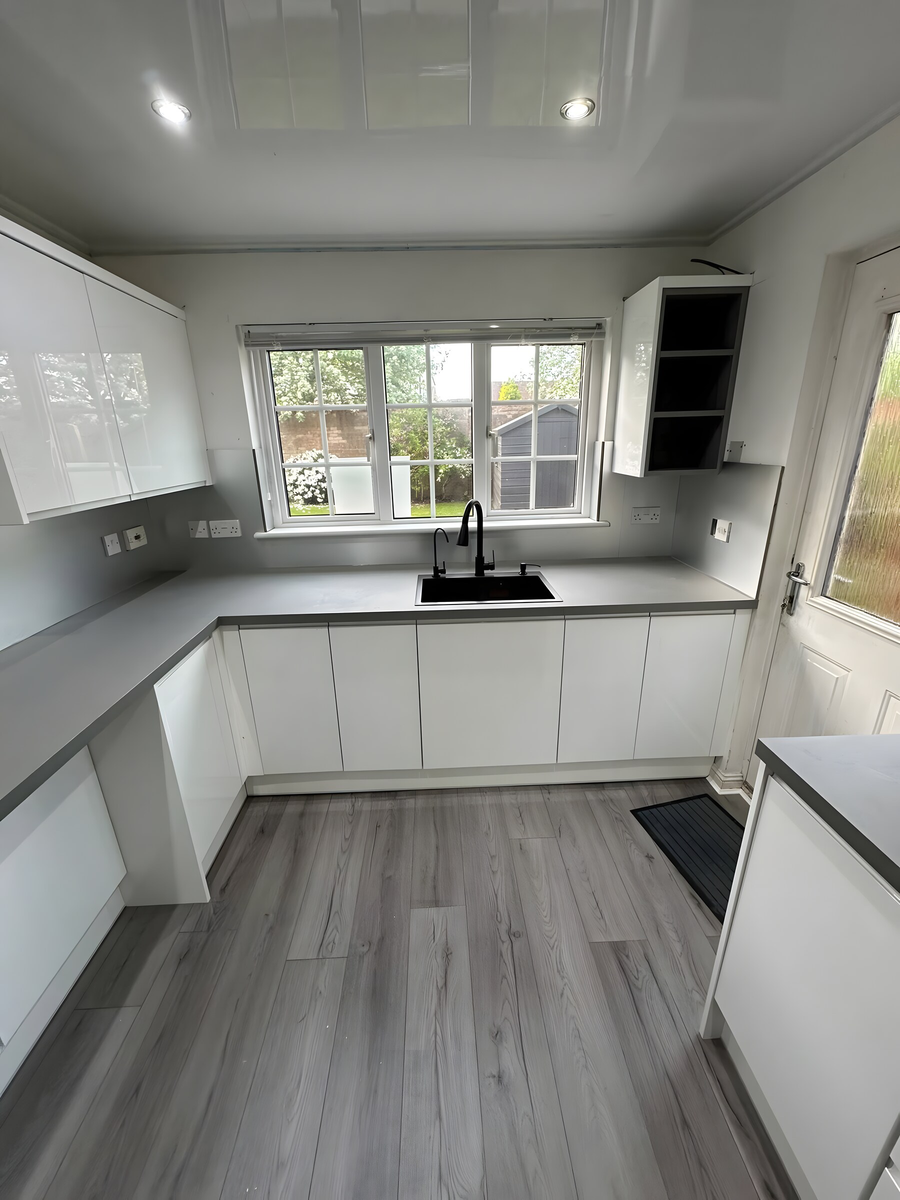 White gloss handleless with a grey worktop and black sink