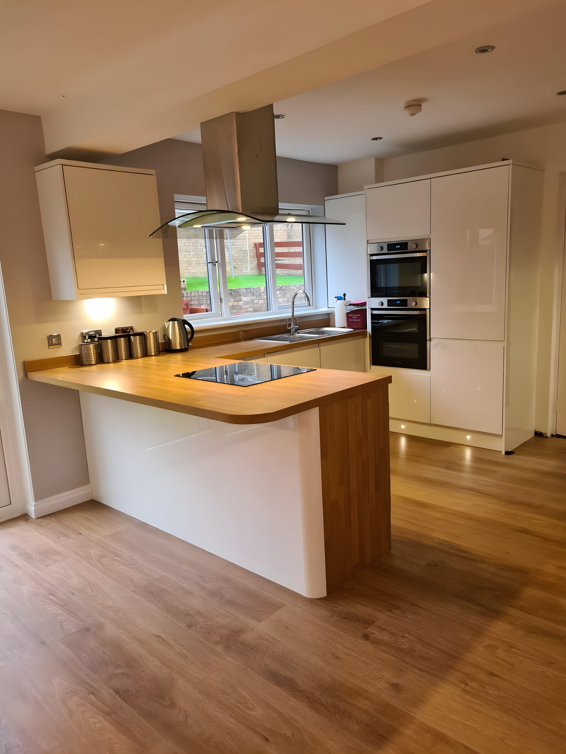 White handleless with an oak peninsula and hob