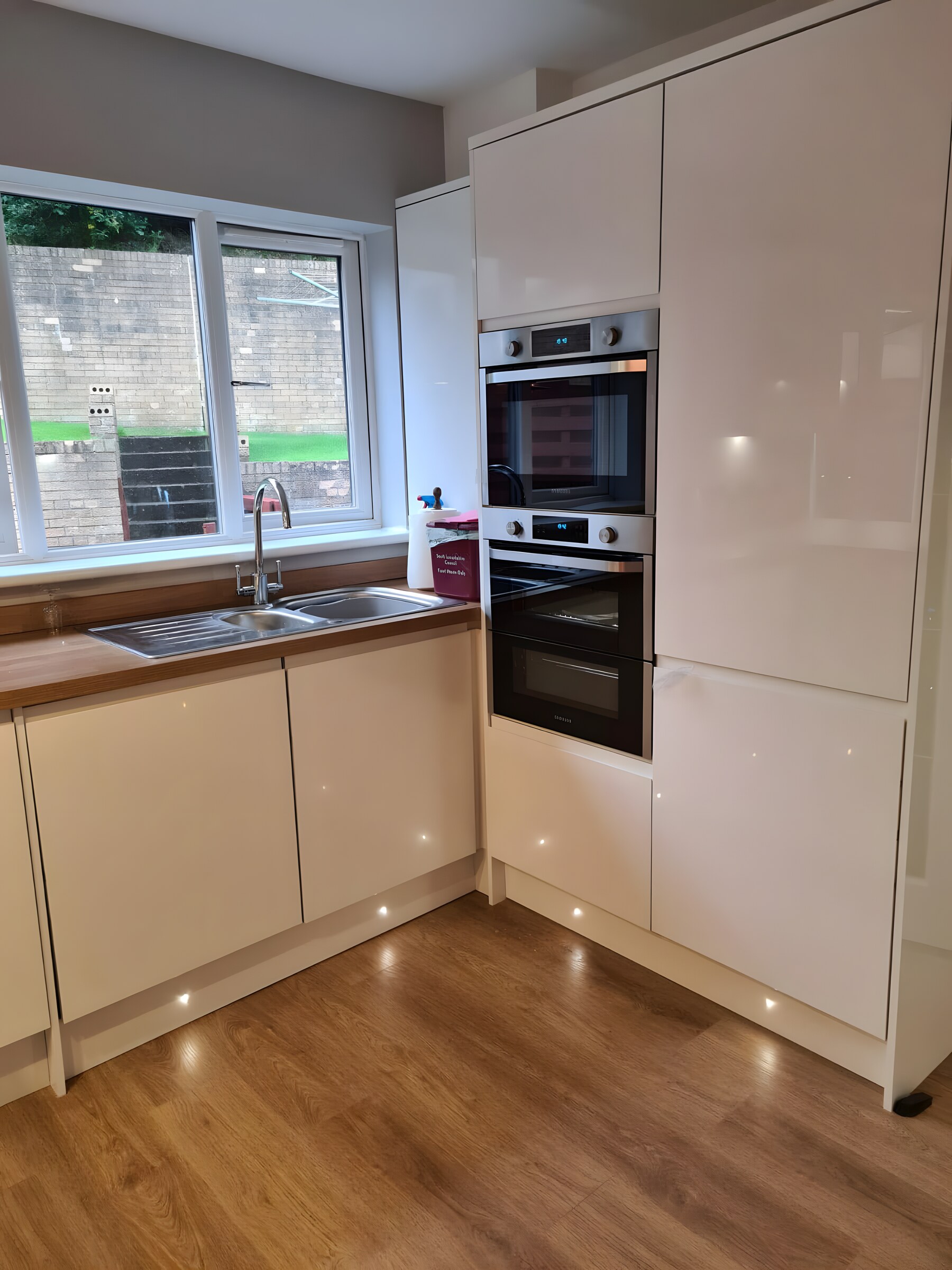 The same white gloss and oak — the L-shaped run to the window